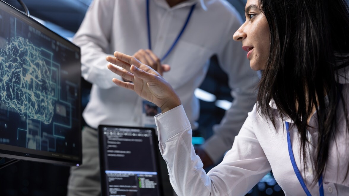 Zwei Personen sprechen miteinander und schauen auf einen Monitor