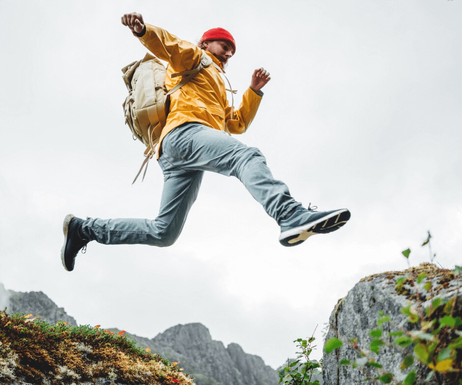 hiker jumping across rocks