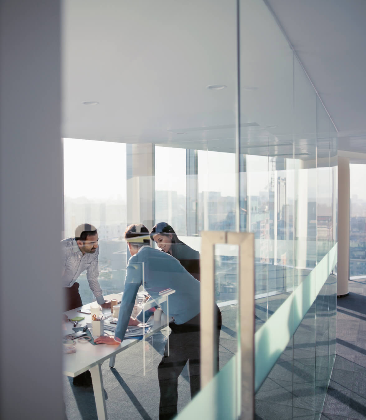Das Business-Team versammelt sich um einen Konferenztisch in einem hellen Büro mit Blick auf die Stadt.
