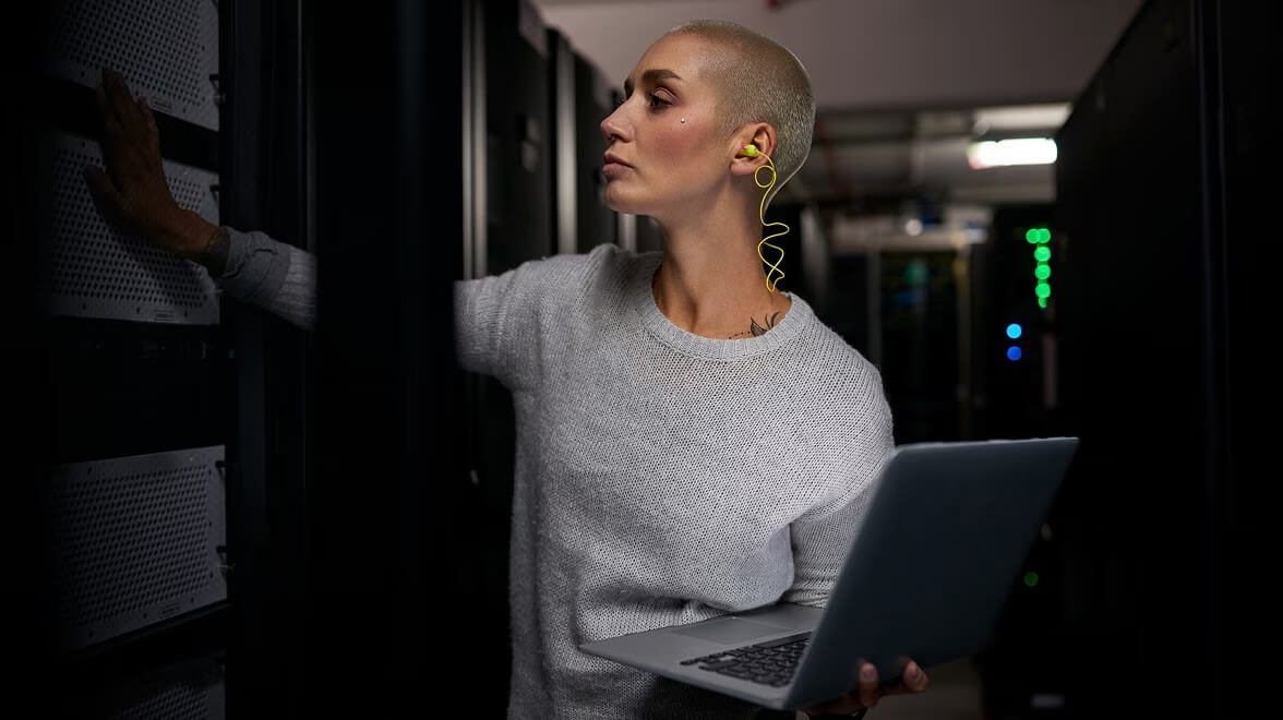Techniker untersucht Servergeräte, während er einen Laptop in einem Rechenzentrum benutzt.