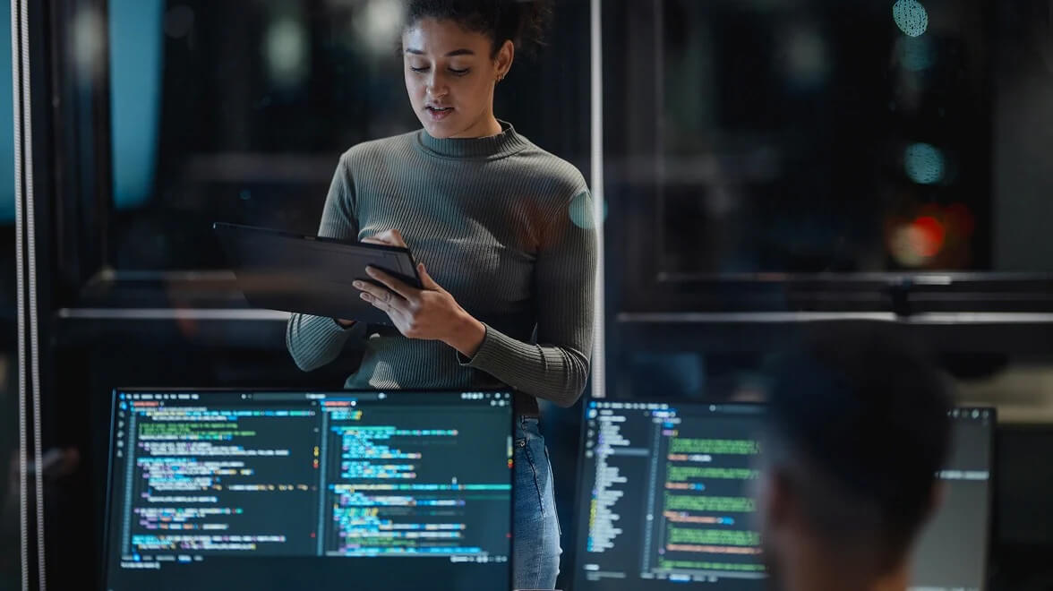 Ein Cybersicherheitsexperte analysiert Code und System-Dashboards in einem sicheren Operationsraum.