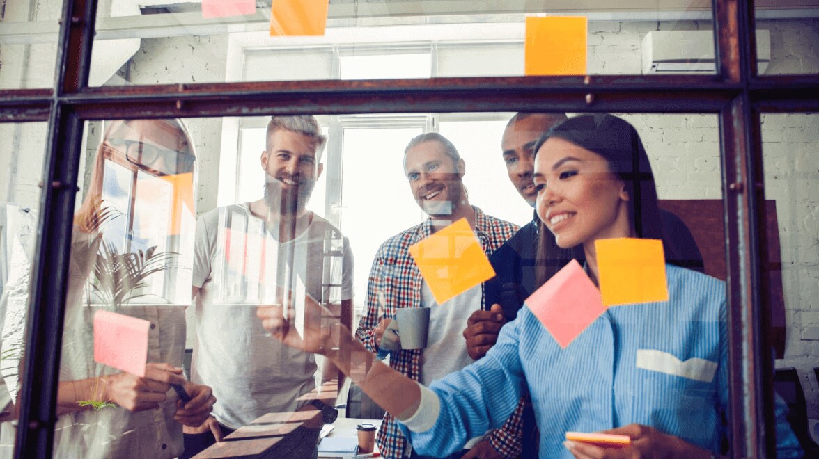 Grupo de personas que pegan notas adhesivas en el marco de cristal
