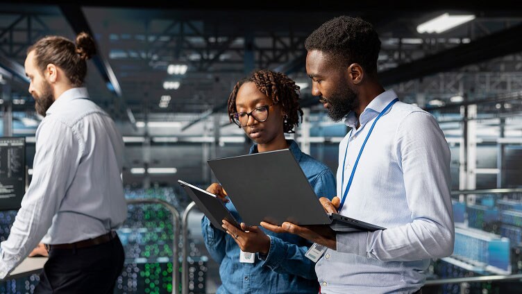 Team che collabora con laptop e tablet all'interno di un ambiente data center.