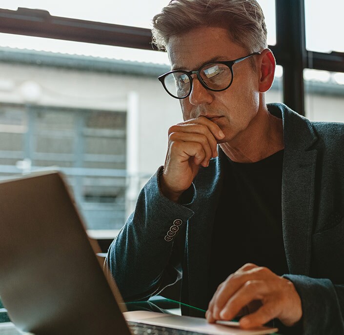 a man thinking in front of laptop