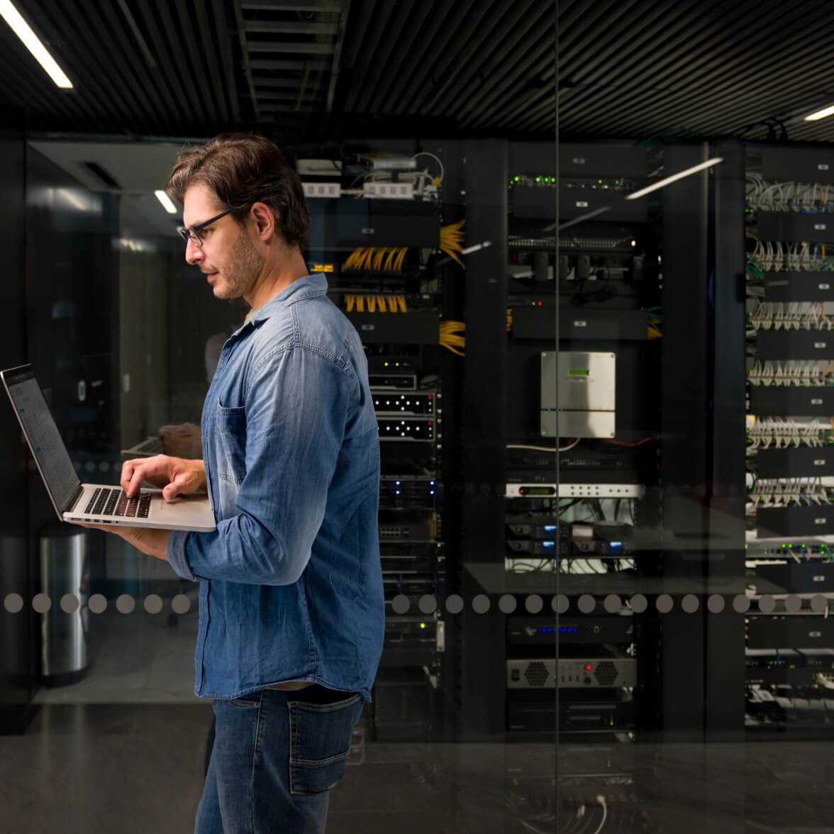 persona che tiene il laptop e cammina nel data center