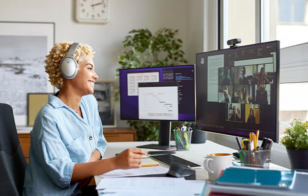 A person sitting in front of monitors with headphones and working