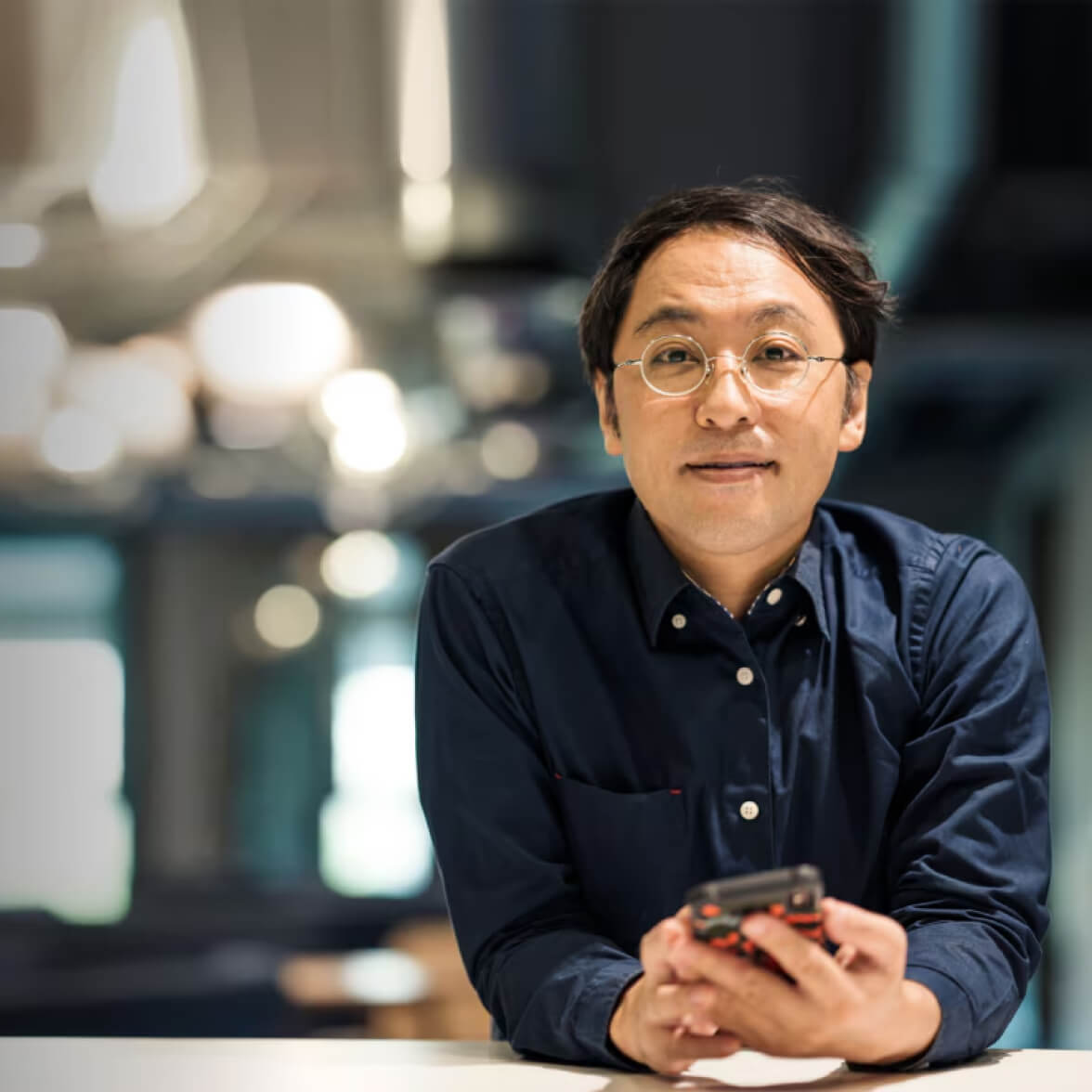 persona che indossa occhiali e tiene il telefono posando per la fotocamera