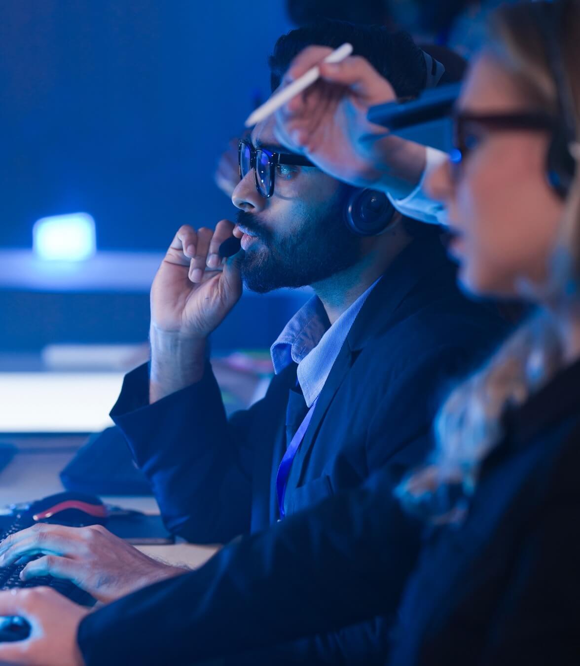 Membri del team che lavorano alle postazioni informatiche in un ambiente operativo tecnologico.