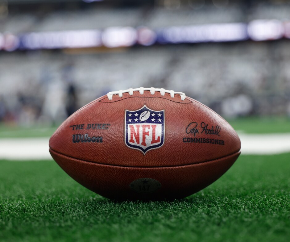 Primo piano di un pallone da football NFL appoggiato sul campo con il logo NFL ben visibile.