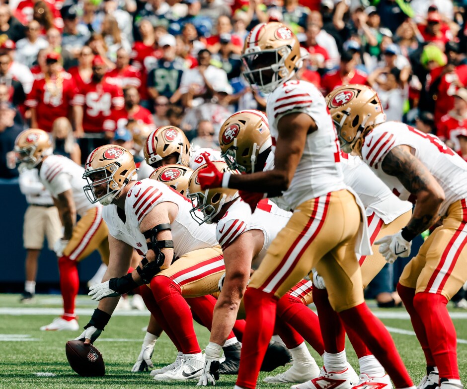 サンフランシスコ 49ers の選手たちは試合中にスクリメージ ラインに並び、スナップに備えている。