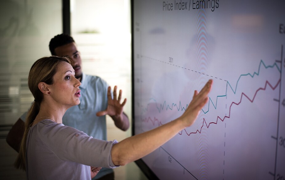 two persons looking at price index and earnings graph going up and studying it
