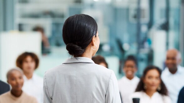 Business professional addressing a group during a workplace meeting or training session.