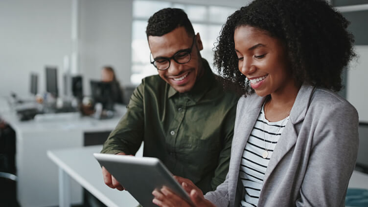 Two persons smiling and looking into the tab