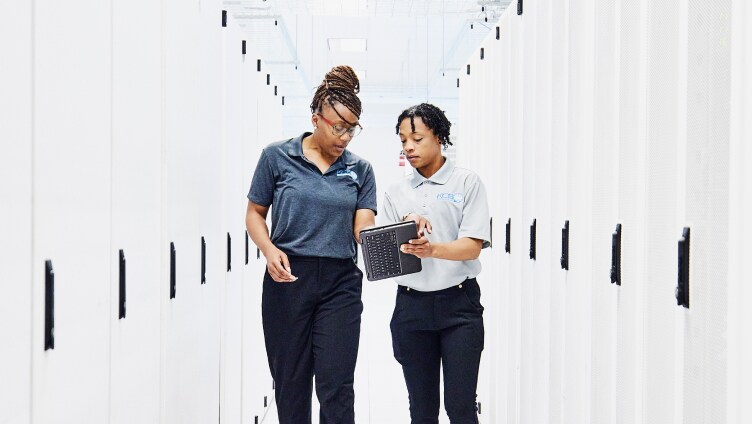 Two People walking and discussing by looking into the tab