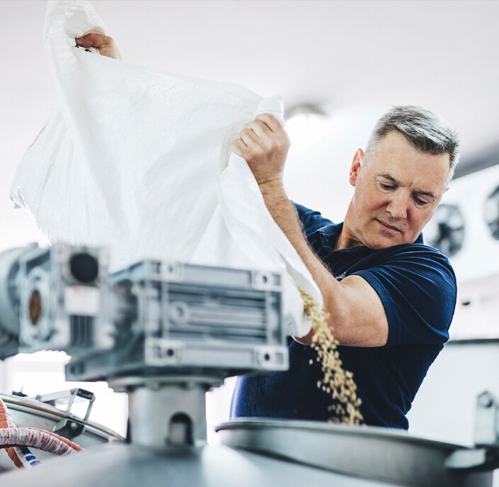 man pouring ingredients into a vat