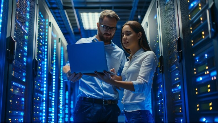 two people inside data center looking into laptop and analyzing inside data center