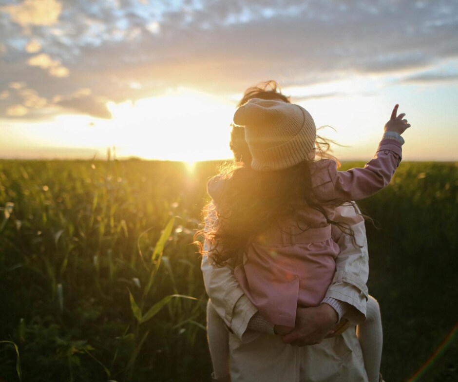 A Person carrying a kid during sunset