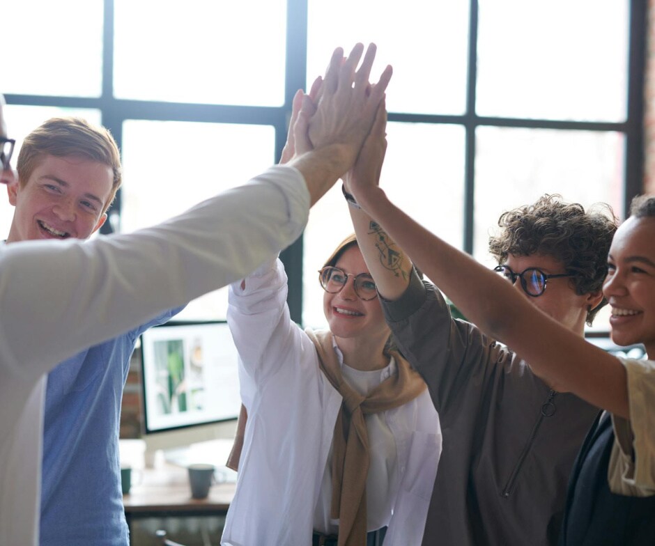 Team of coworkers giving a high five in a modern office, symbolizing collaboration, teamwork, and workplace success.