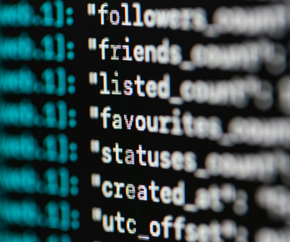 Close-up of computer screen displaying code with data fields such as followers, friends, and statuses.
