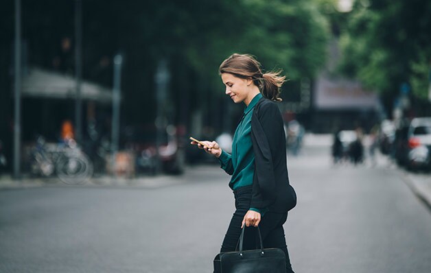 woman looking at phone while crossing the street