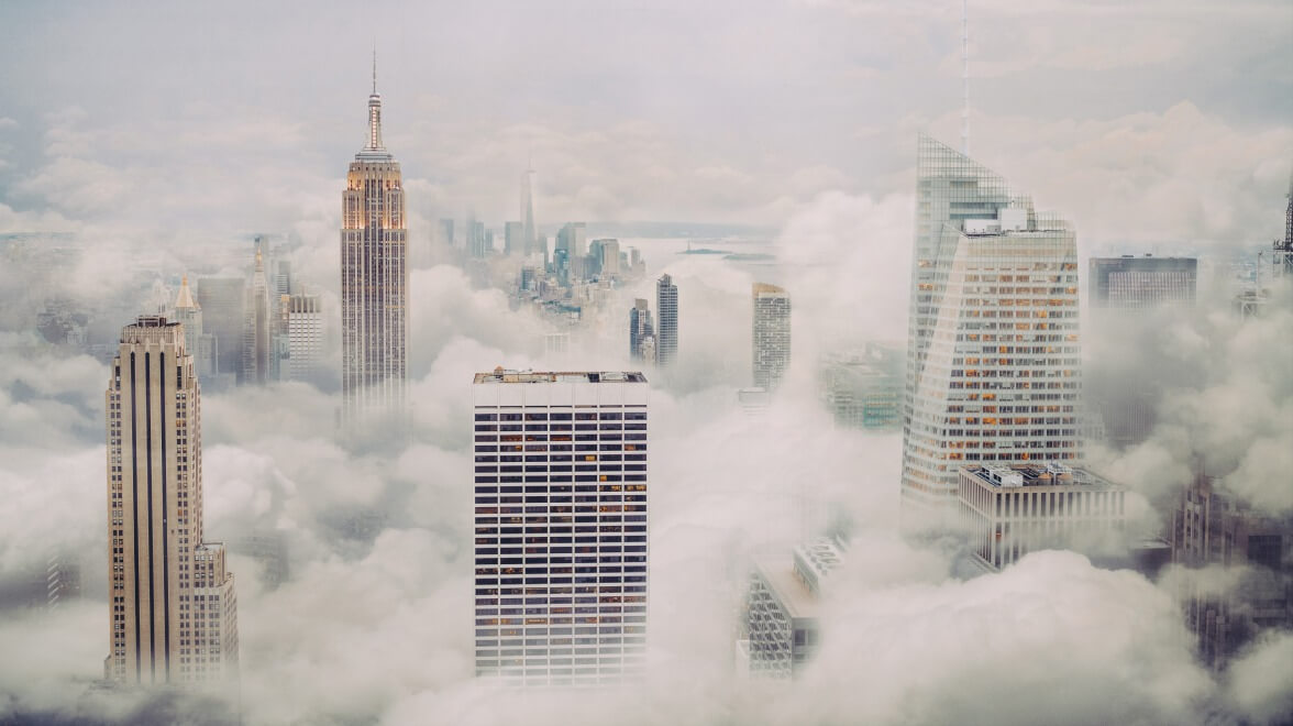 City skyline with tall skyscrapers emerging through thick clouds in a modern metropolitan area.