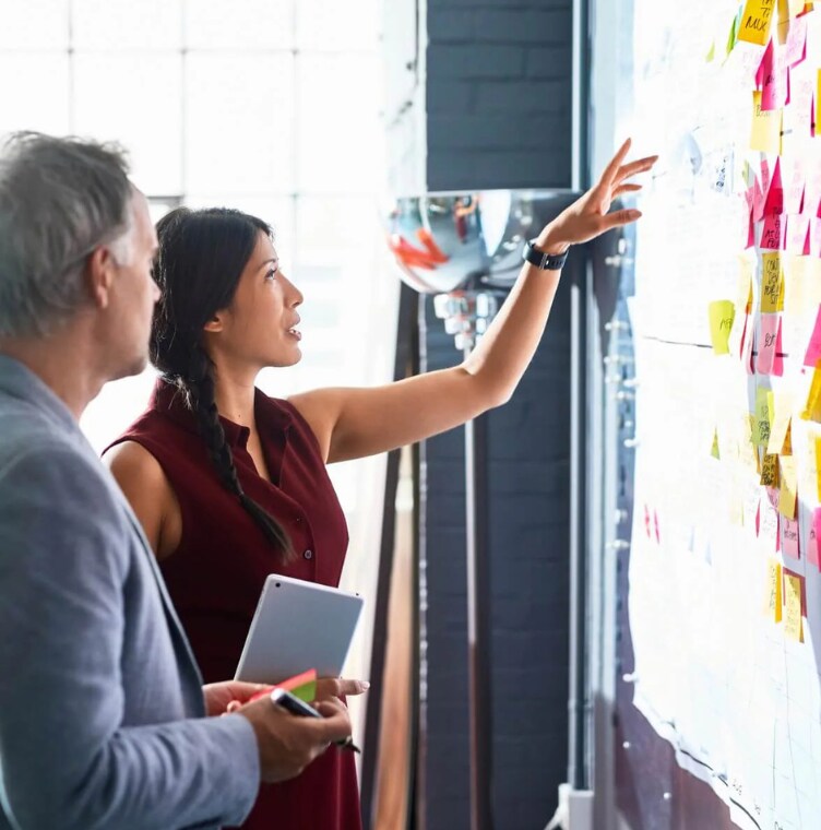 pessoas discutindo olhando para post-its no quadro