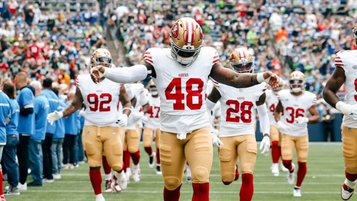 Jogadores do San Francisco 49ers correndo para o campo antes do início da partida.