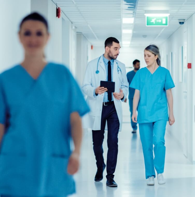 Mostrando a equipe médica caminhando por um corredor de hospital durante uma atividade clínica de rotina.