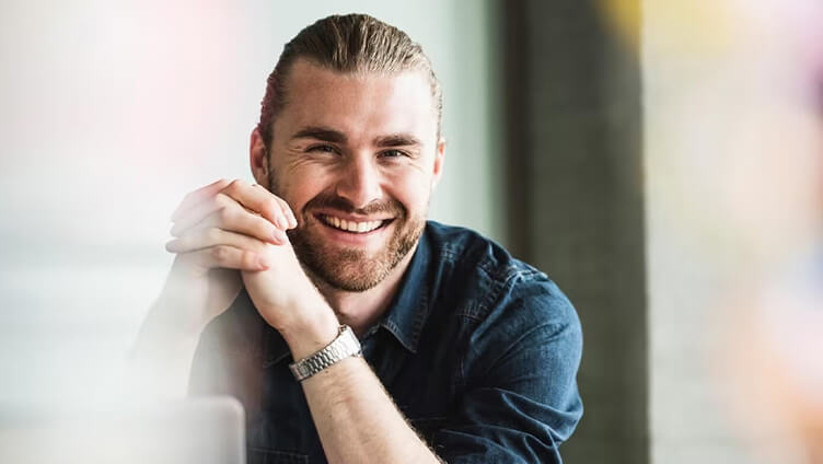 一个人坐在办公桌前，双手紧握，在现代办公环境中显得深思熟虑。