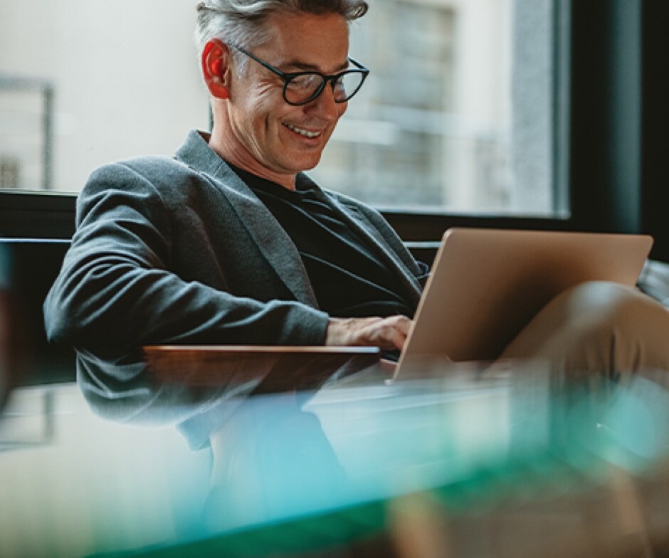 一位男士看着笔记本电脑微笑