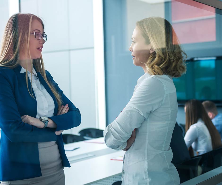 两位女性同事在会议室中交谈
